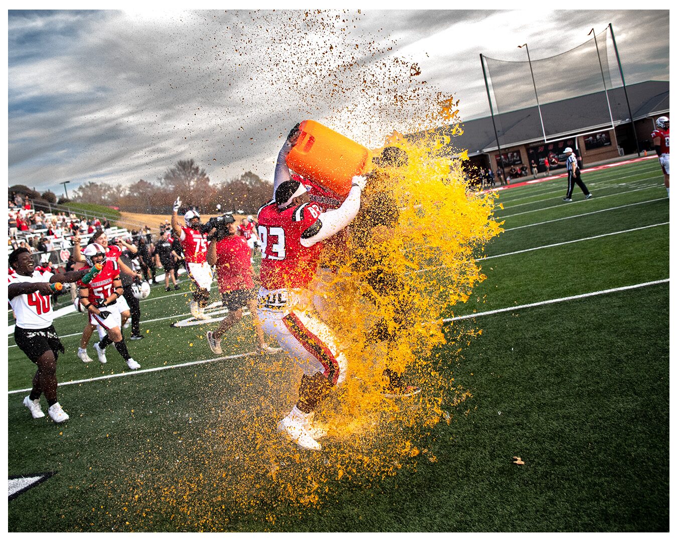 A Gatorade bucket splashes orange in celebration on the NGU field.