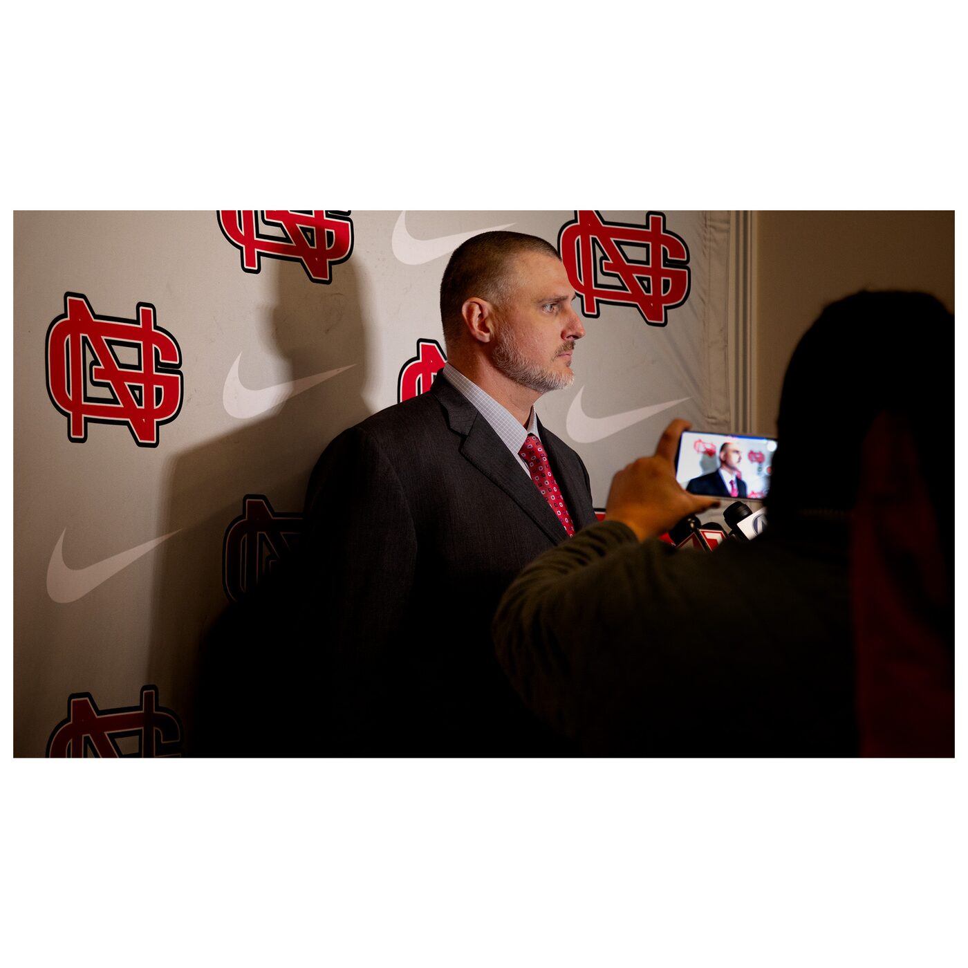 Coach Garner speaks at an NGU press event in front of a branded step-and-repeat.